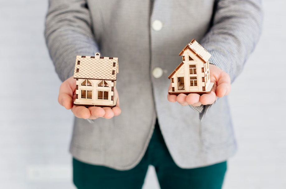 Person holding two miniature house models in each hand