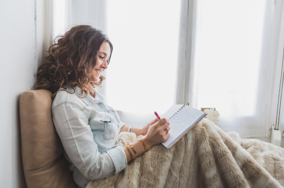 Woman smiling while journaling in a notebook for mental clarity and creativity.