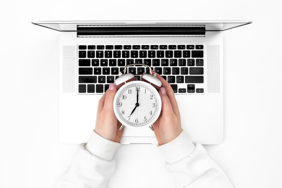 Analog alarm clock over a laptop keyboard, symbolizing mindful tech habits
