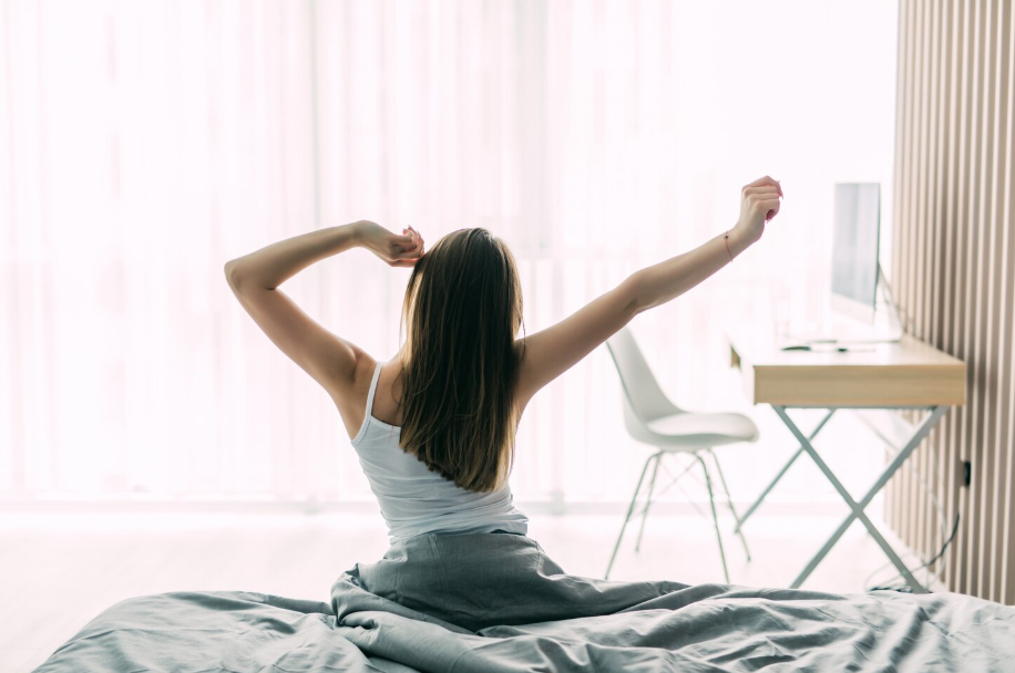 Woman stretching in bed at sunrise as part of a science-backed morning routine