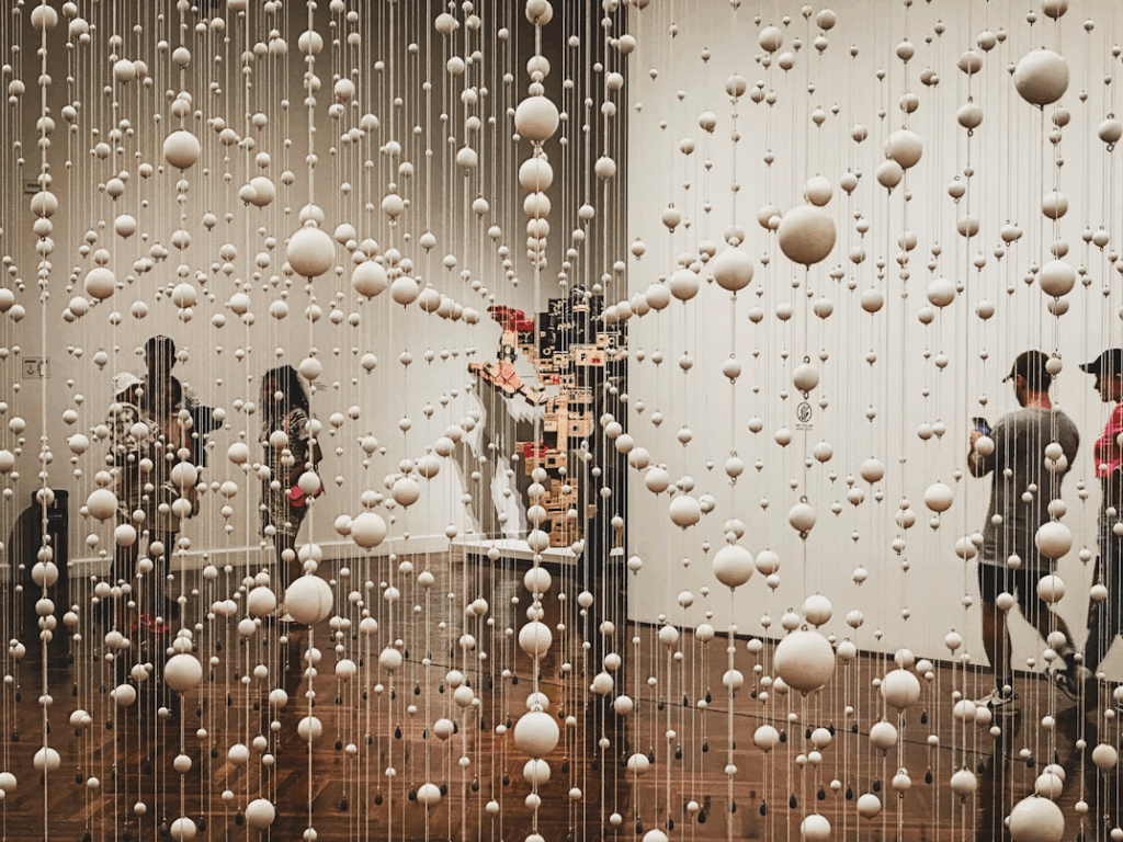 Visitors walking through a museum’s hanging sphere installation