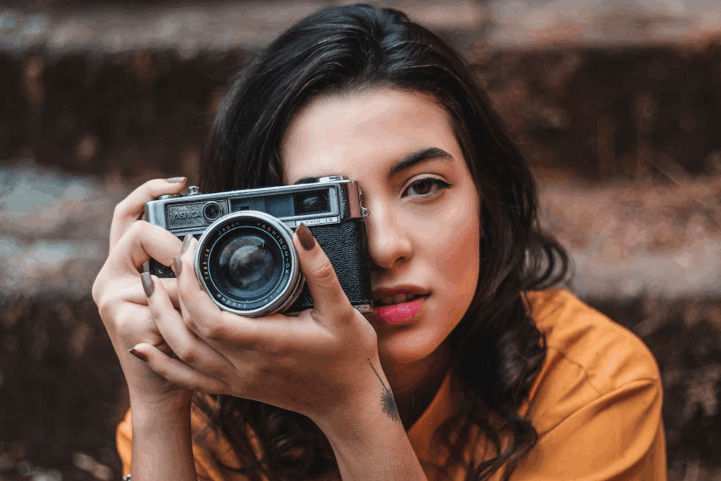 Woman holding a vintage film camera close to her face