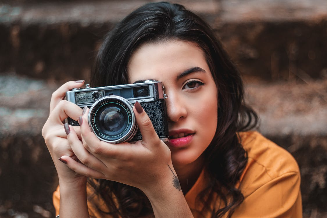 Woman holding a vintage film camera close to her face