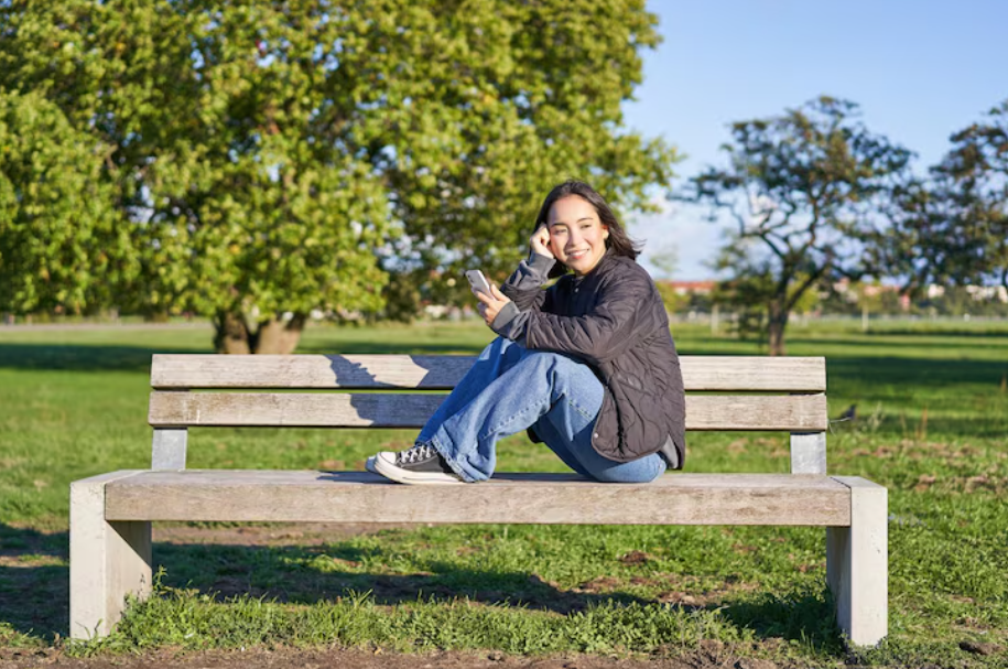 Woman sitting on a park bench on a sunny day, enjoying the benefits of green space