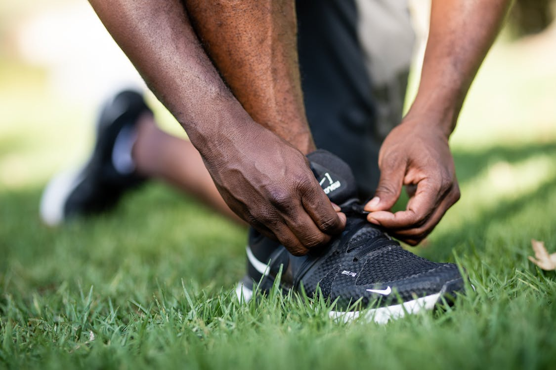 Lacing black running shoes, symbolizing building grit without burnout through steady effort.