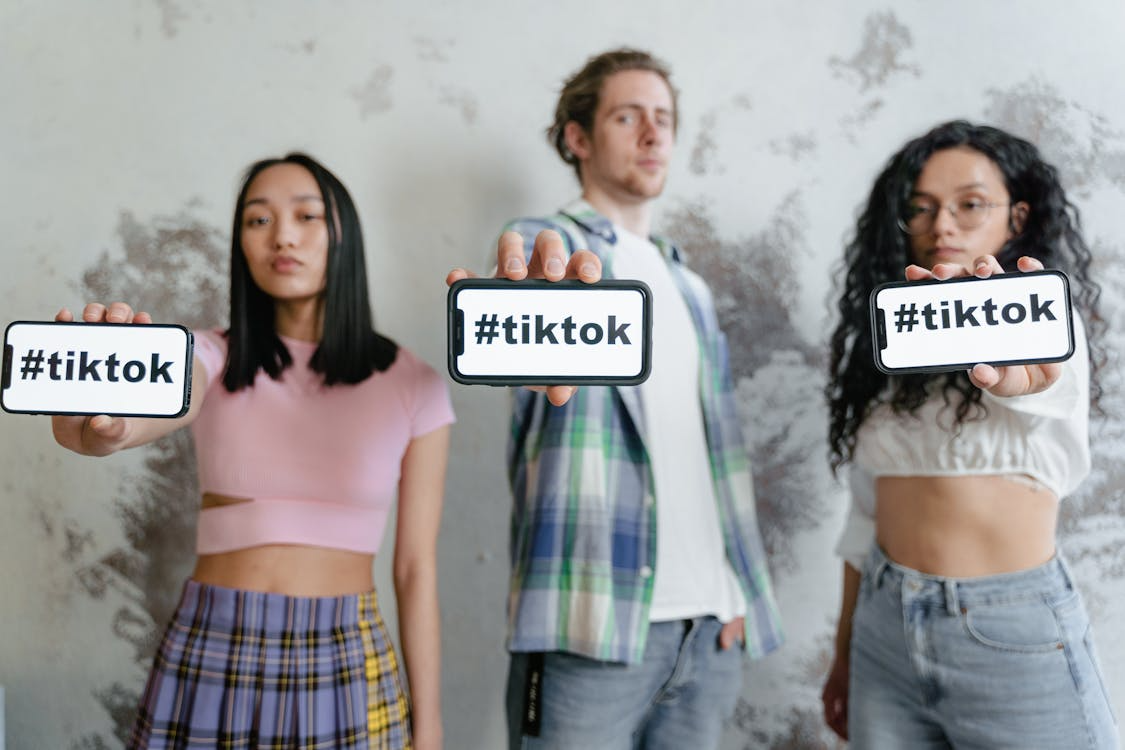 Creators presenting phones with #tiktok, illustrating the viral trend psychology